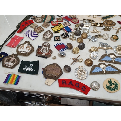 225 - A bag of Military Badges and other items including SAS Belt, Cloth Badges, Royal Engineers Cap Badge... 