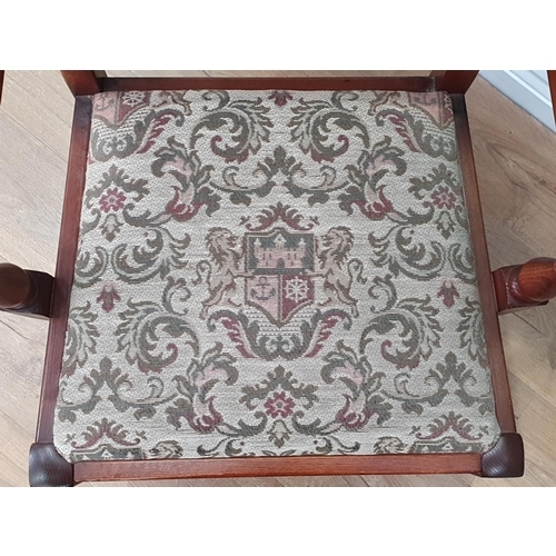 31 - An oak Elbow Chair with carved and arched back with coat of arms and floral upholstery on turned and... 