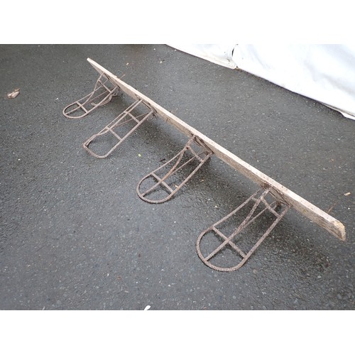 255 - Four old metal saddle Racks mounted on a wooden board, approx 6ft