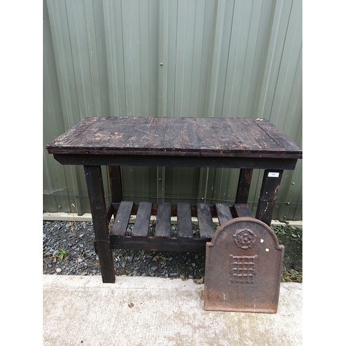 634 - A stained wood two-tier Work Table and a small cast iron Fireback