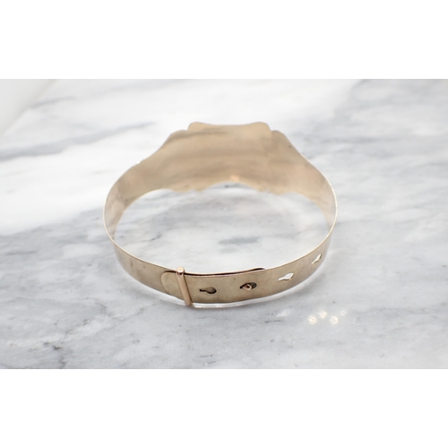 154 - A gold Bangle the front with bright-cut engraving on buckle effect clasp, stamped 9ct, approx 9gms