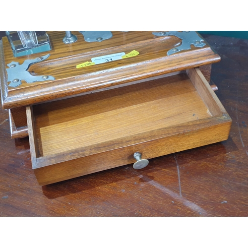 31 - An oak Inkstand with metal mounts and metal arched handle, with pair of glass inkwells above single ... 