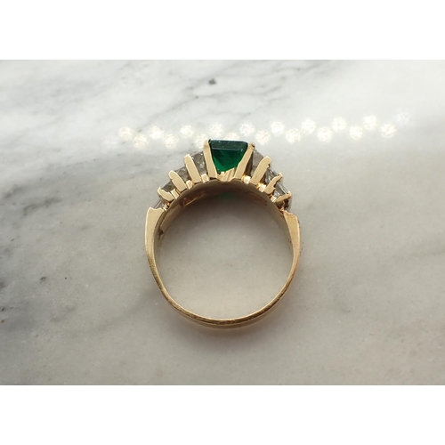 153 - An Emerald and Diamond Ring channel-set step-cut emerald between graduated pairs of princess-cut dia... 