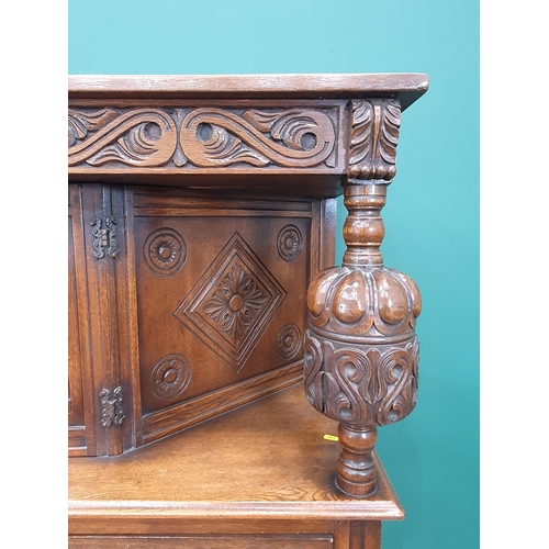 34 - A reproduction oak Court Cupboard with central cupboard flanked by turned columns, above pair of fit... 