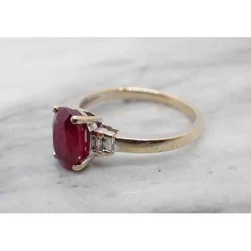 124 - A Ruby and Diamond Ring claw-set oval-cut ruby between two pairs of channel-set baguette diamonds in... 