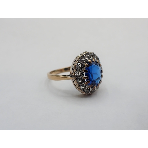 131 - A 9ct gold Cluster Ring claw-set oval blue synthetic spinel within a frame of white stones, ring siz... 