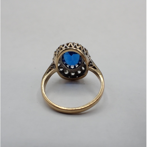 131 - A 9ct gold Cluster Ring claw-set oval blue synthetic spinel within a frame of white stones, ring siz... 