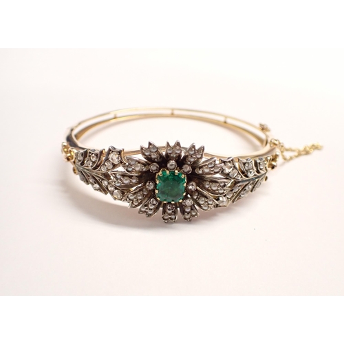 207 - An Emerald, Seed Pearl and Diamond hinged Bangle the front with flower effect claw-set step-cut emer... 