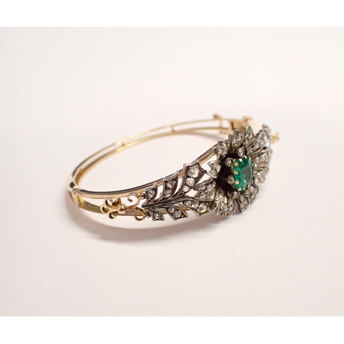 207 - An Emerald, Seed Pearl and Diamond hinged Bangle the front with flower effect claw-set step-cut emer... 