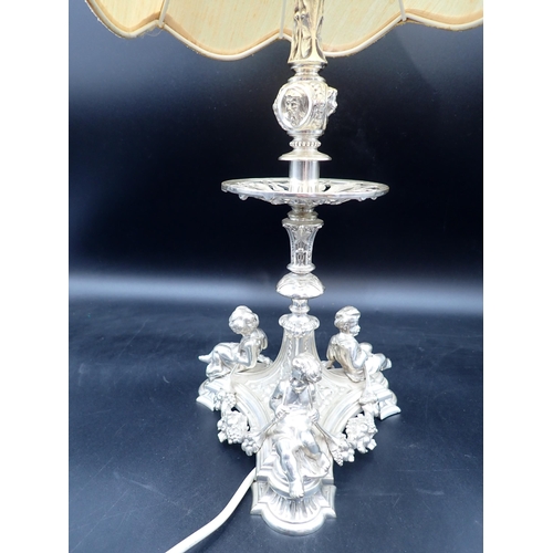 31 - A plated Table Lamp with mask decorated column on triangular base with three cherubs holding floral ... 