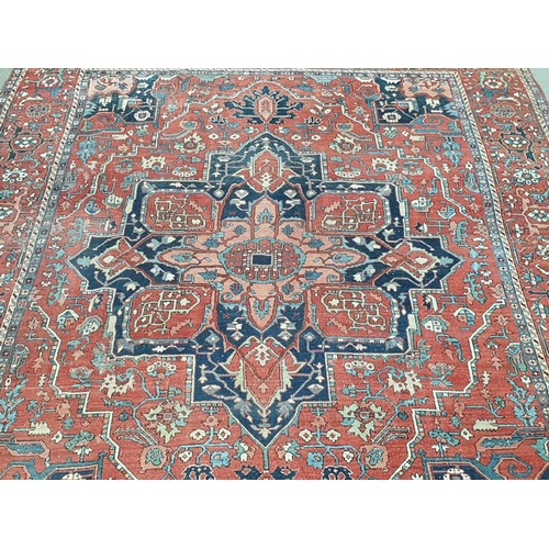 386 - A Heriz Rug with central all over geometric designs in blue, geometric pattern border, on a red grou... 