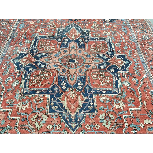 386 - A Heriz Rug with central all over geometric designs in blue, geometric pattern border, on a red grou... 