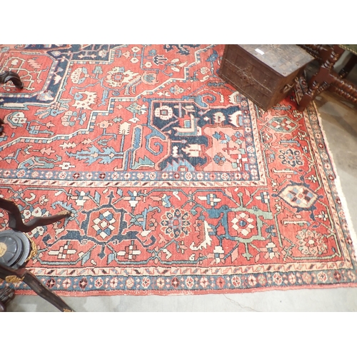 386 - A Heriz Rug with central all over geometric designs in blue, geometric pattern border, on a red grou... 