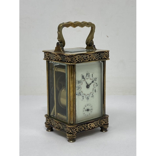 530 - A French small brass Carriage Clock with hinged handle, floral scrolled frieze decoration, the white... 