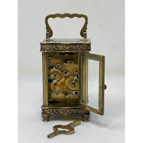 530 - A French small brass Carriage Clock with hinged handle, floral scrolled frieze decoration, the white... 