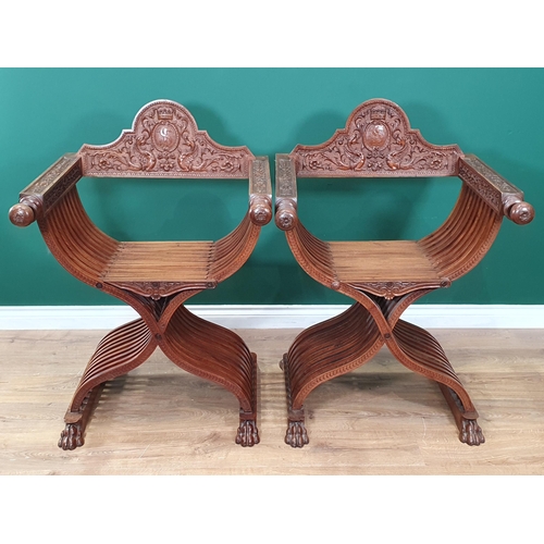 558 - A pair of walnut X-framed Thrones with carved Armorial top rails and trailing floral and ivy leaf de... 