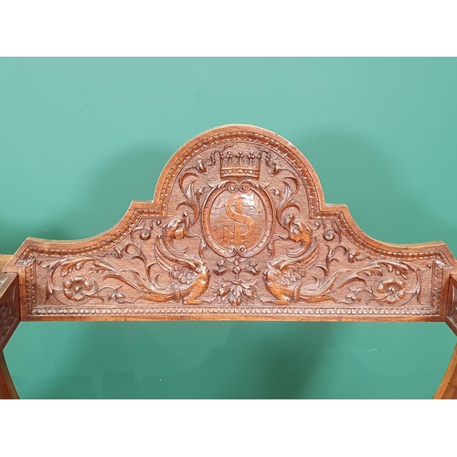 558 - A pair of walnut X-framed Thrones with carved Armorial top rails and trailing floral and ivy leaf de... 