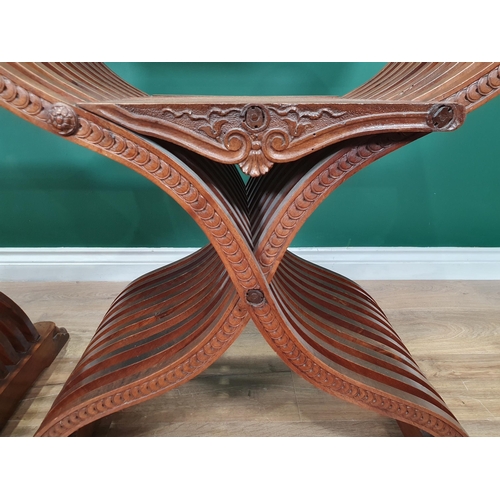 558 - A pair of walnut X-framed Thrones with carved Armorial top rails and trailing floral and ivy leaf de... 