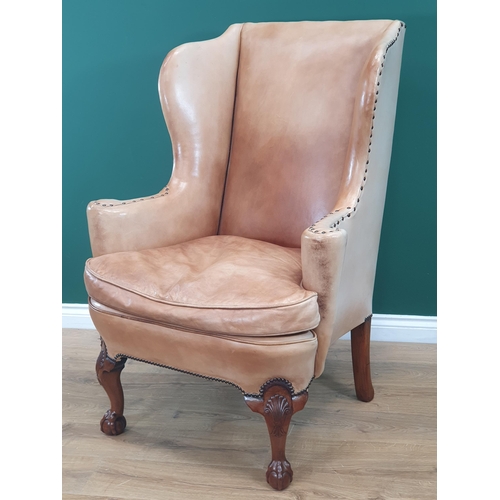 568 - A George III style walnut Wingback Armchair in pale tan leather with outswept arms, raised on carved... 