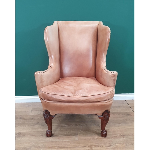 568 - A George III style walnut Wingback Armchair in pale tan leather with outswept arms, raised on carved... 