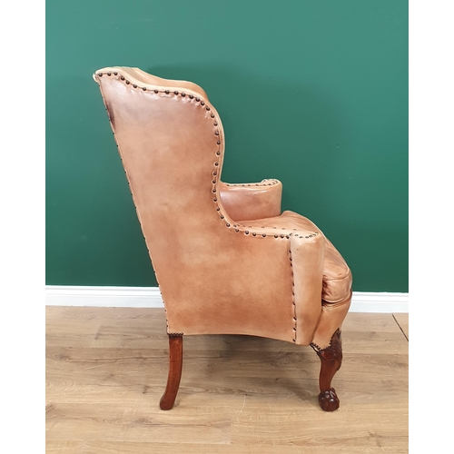 568 - A George III style walnut Wingback Armchair in pale tan leather with outswept arms, raised on carved... 