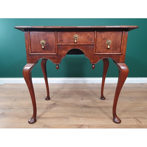 636 - A Georgian walnut Lowboy with quarter veneered, feather banded top above three drawers surrounding a... 