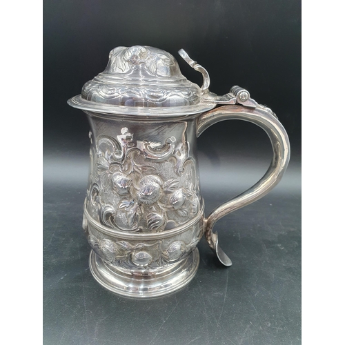 150 - A George II silver Tankard with floral embossing, rococo cartouche engraved coat of arms and motto, ... 