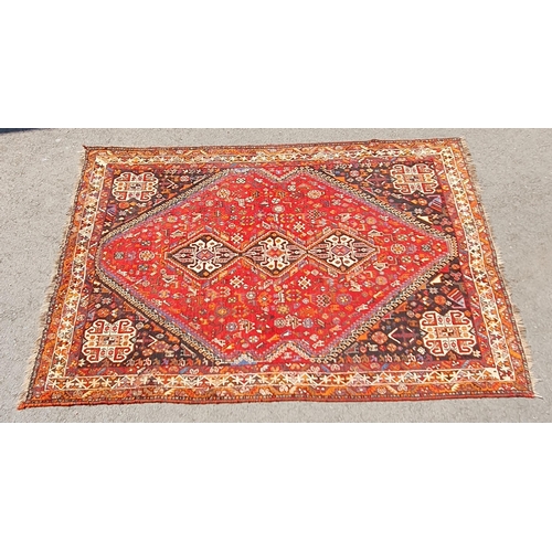 3 - A Persian style Carpet with multiple borders with three lozenges within a large lozenge on a red gro... 