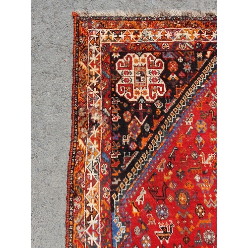 3 - A Persian style Carpet with multiple borders with three lozenges within a large lozenge on a red gro... 