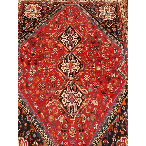 3 - A Persian style Carpet with multiple borders with three lozenges within a large lozenge on a red gro... 