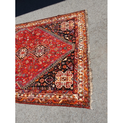 3 - A Persian style Carpet with multiple borders with three lozenges within a large lozenge on a red gro... 