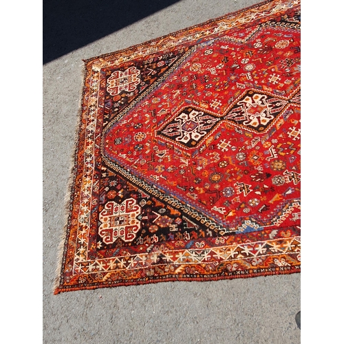 3 - A Persian style Carpet with multiple borders with three lozenges within a large lozenge on a red gro... 