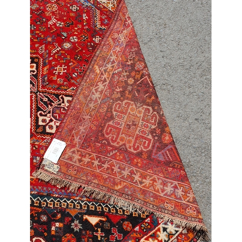 3 - A Persian style Carpet with multiple borders with three lozenges within a large lozenge on a red gro... 