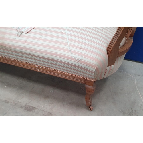 400 - An Edwardian oak framed Chaise Longue with carved decoration, striped upholstery, raised on squat ca... 