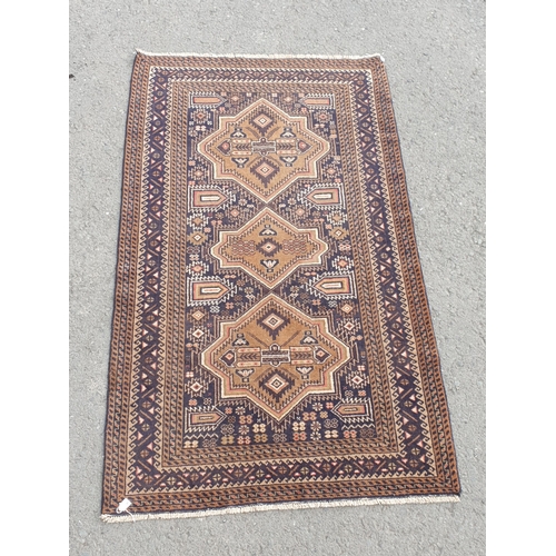 739 - A Persian Rug with multiple borders and three shaped medallions on a dark blue ground, 6ft 3in x 3ft... 