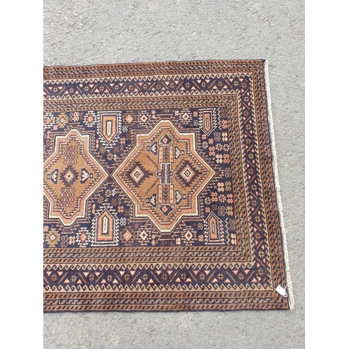 739 - A Persian Rug with multiple borders and three shaped medallions on a dark blue ground, 6ft 3in x 3ft... 