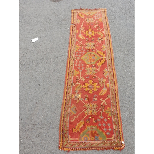 742 - A Turkish type Runner with stylised floral motifs on a red ground, worn and damaged, 11ft 8in x 3ft ... 