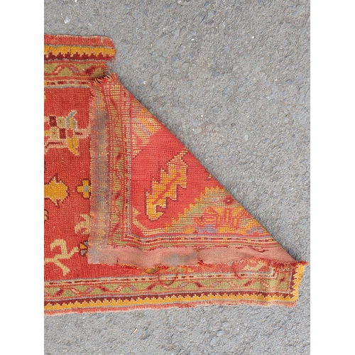 742 - A Turkish type Runner with stylised floral motifs on a red ground, worn and damaged, 11ft 8in x 3ft ... 