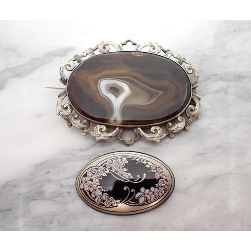 155 - An oval Agate Brooch in engraved openwork white metal frame, together with a small oval enamel Brooc... 