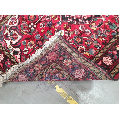 207 - A small Persian Rug with floral border and floral motifs on a red ground, 5ft x 3ft 4in