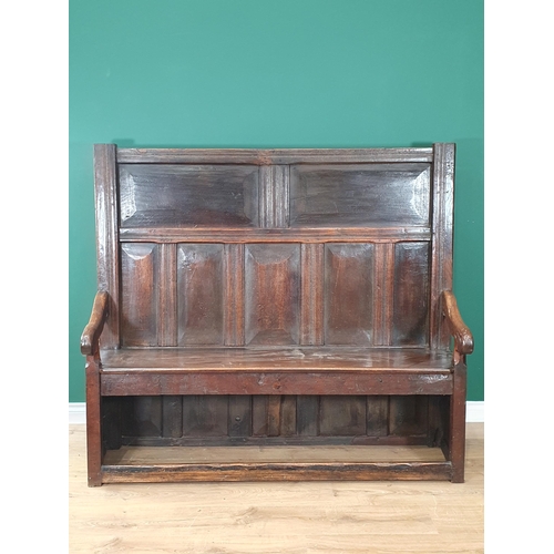 28 - An early 18th Century and later oak Settle with panelled back, shaped arms and squared front stretch... 