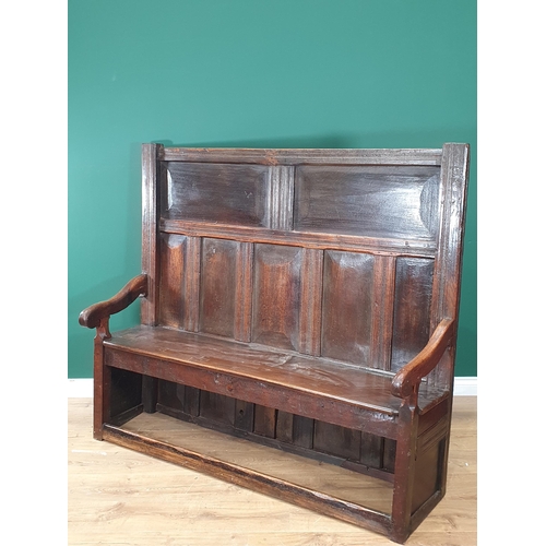 28 - An early 18th Century and later oak Settle with panelled back, shaped arms and squared front stretch... 