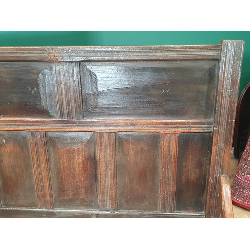 28 - An early 18th Century and later oak Settle with panelled back, shaped arms and squared front stretch... 