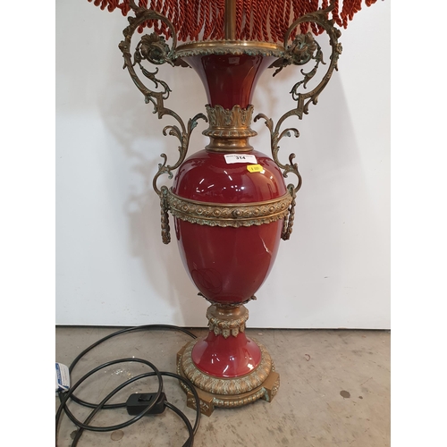 314 - A large red glazed Table Lamp and Shade with elaborate scrolled brass handles, 40in H, passed PAT