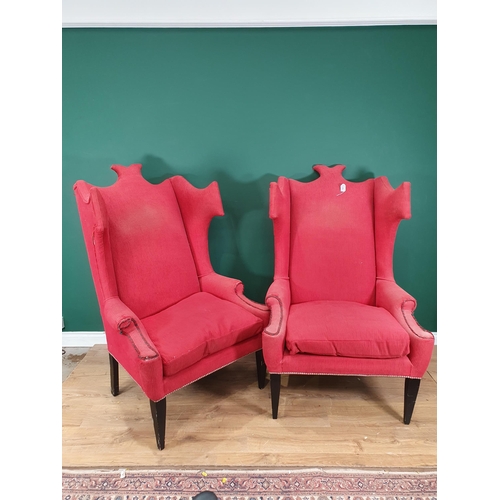 707 - A large pair of red upholstered Wing Back Armchairs with shaped backs, on ebonised tapered supports.