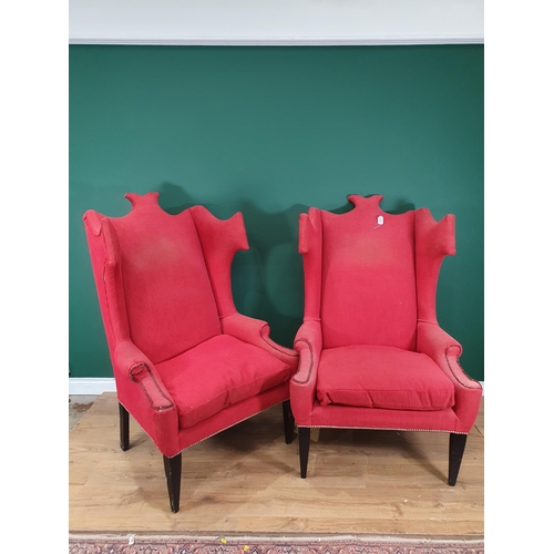 707 - A large pair of red upholstered Wing Back Armchairs with shaped backs, on ebonised tapered supports.