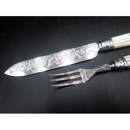 87 - A Victorian serving Knife and Fork with finely scroll engraved silver blades with Mother of Pearl ha... 