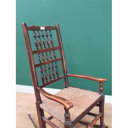 32 - An oak and elm rush seated Spindle back Rocking Chair, on metal rockers.