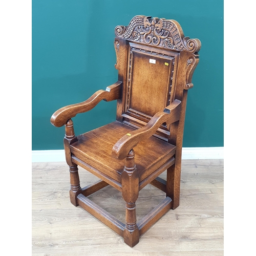 48 - An oak Wainscot Armchair in the 17th Century style with carved serpent cresting rail above plain pan... 