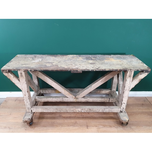 581 - A painted industrial Artists Table/Bench on square supports and stretchers and large metal castors, ... 